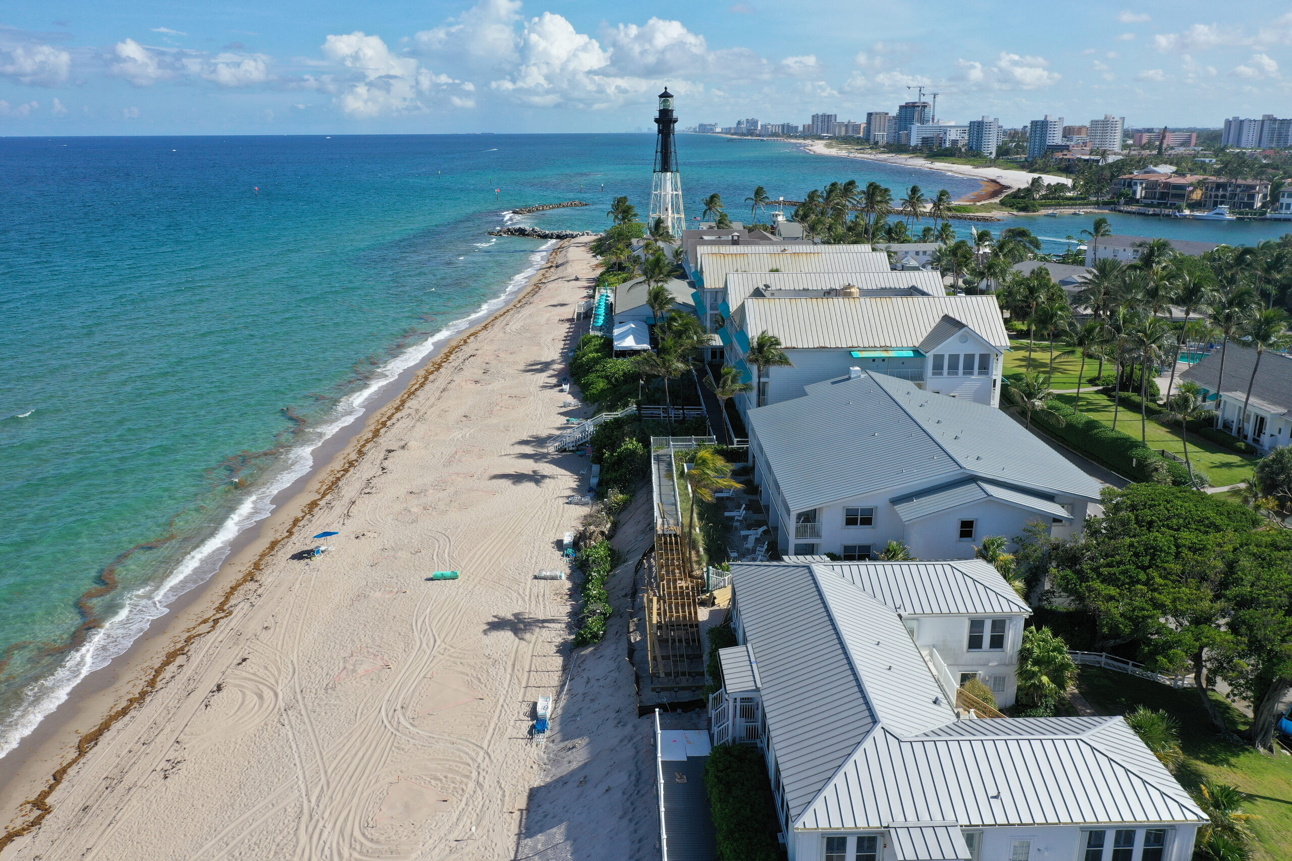 Aerial view of a sandy shoreline with waterfront homes and a lighthouse
