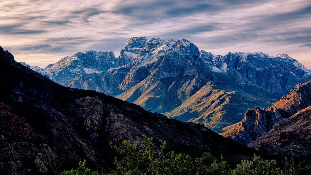 Mountain range with dramatic clouds and shadows.